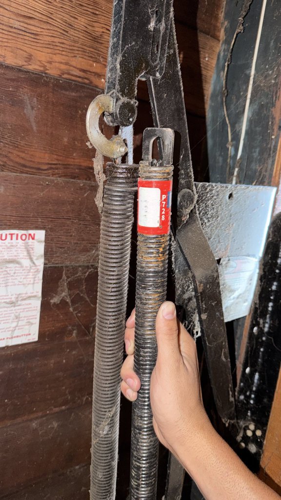MSB technician inspecting worn garage door springs by hand during a spring replacement in Los Angeles