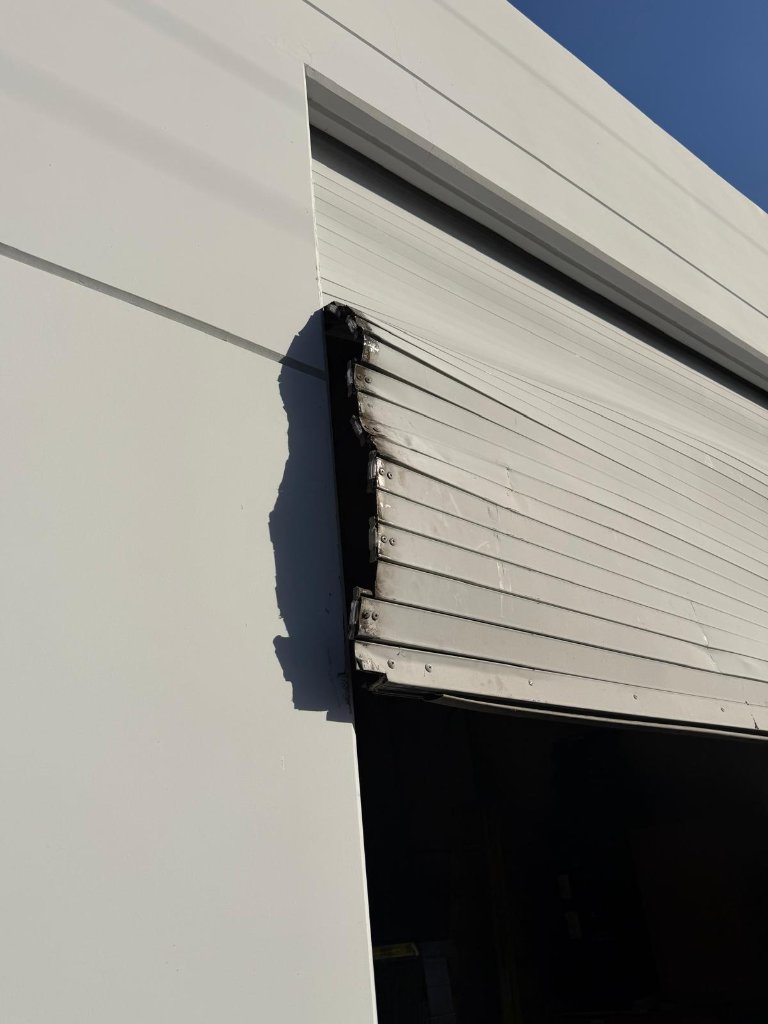 Commercial garage door section jumped off its track at the top corner, emergency off-track repair in Los Angeles