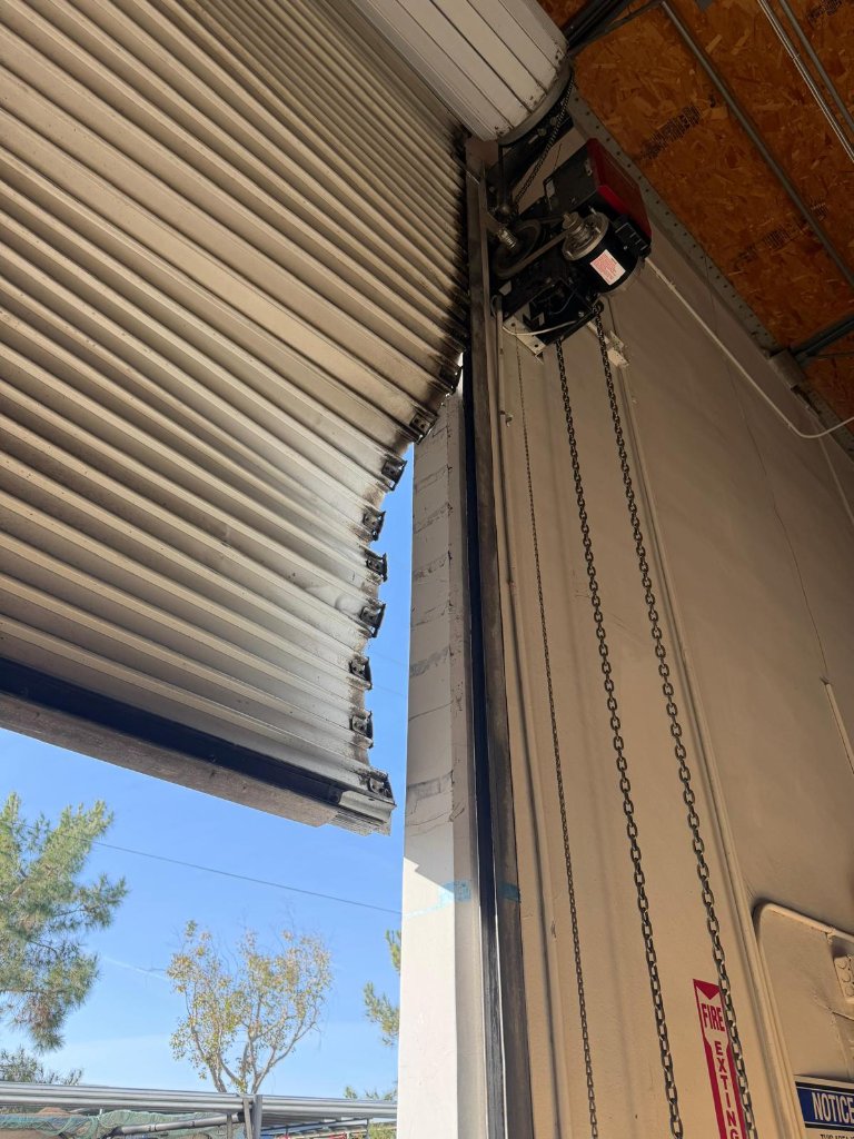 Wide view of corrugated steel commercial garage door repair job in progress at Los Angeles business