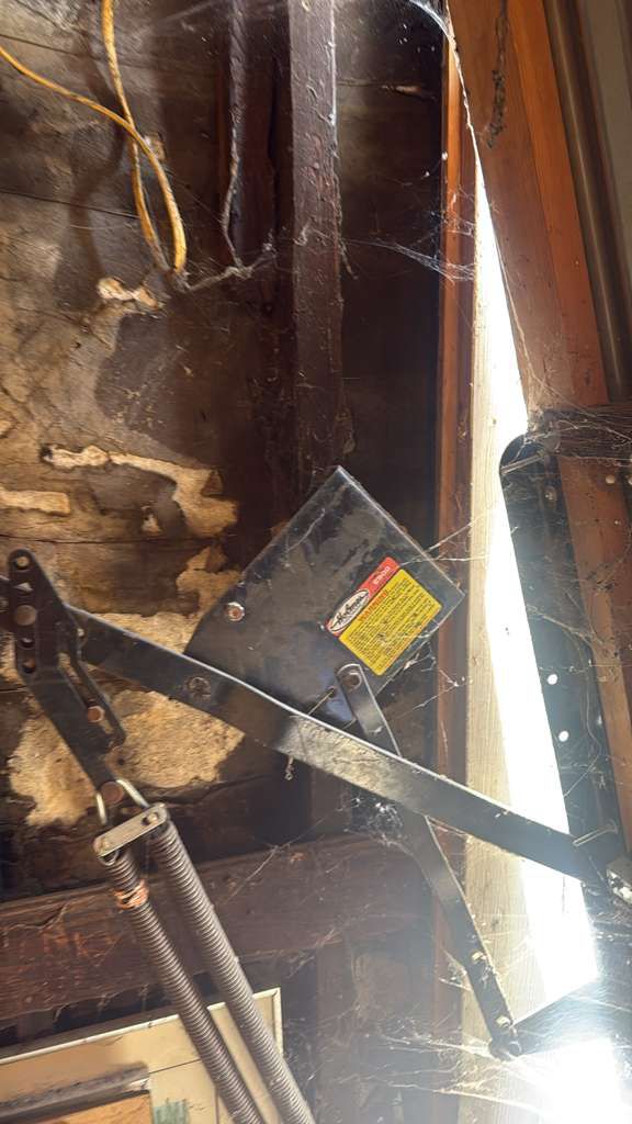 Old worn garage door extension spring hardware in a Los Angeles garage before professional spring replacement